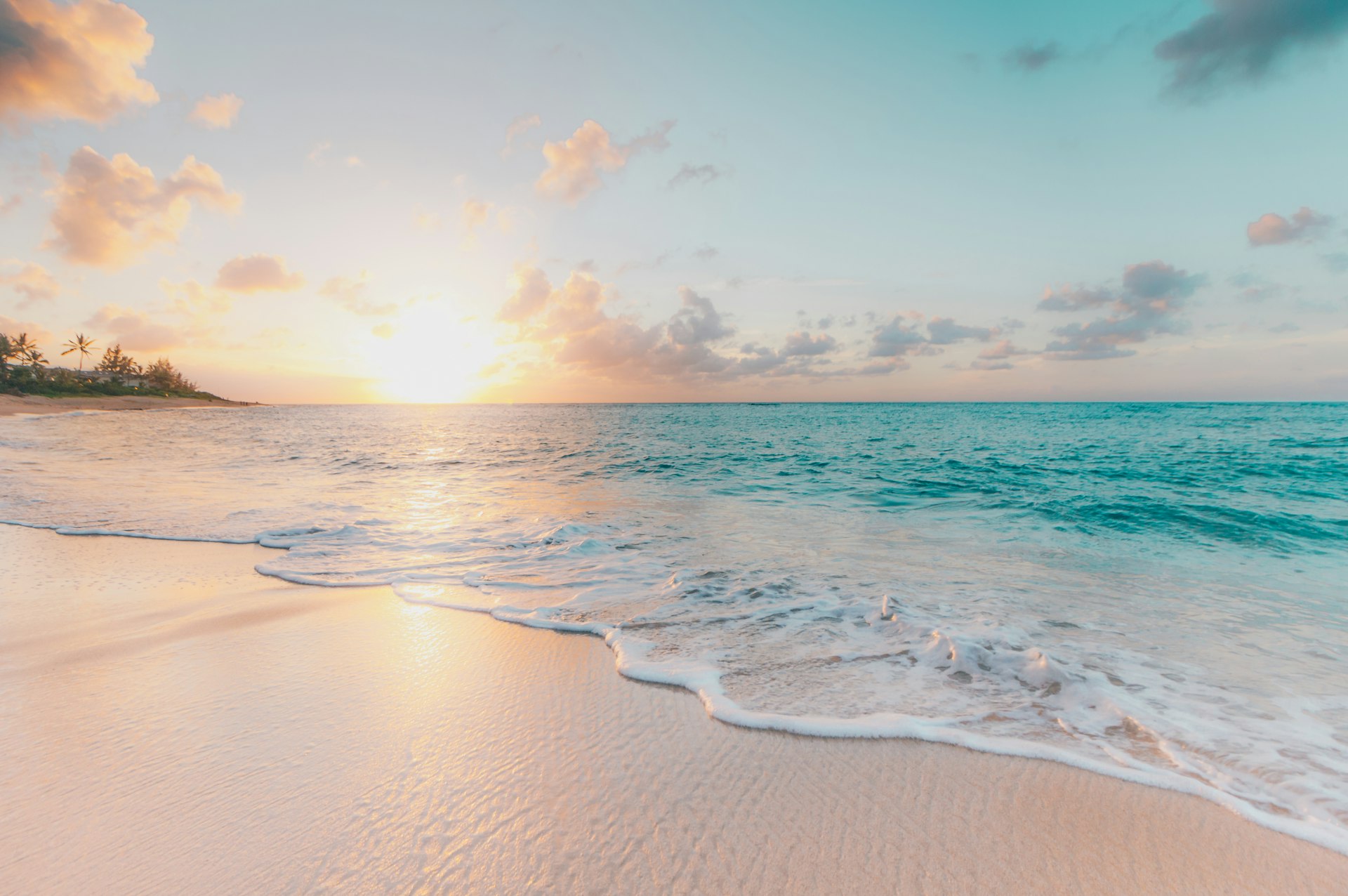 Golden-hour coastline with turquoise waves meeting a pale sand beach