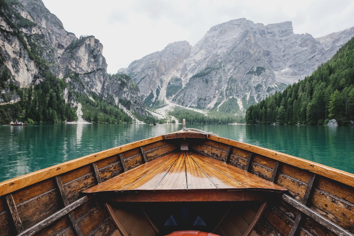 Wooden boat pointing toward dramatic mountains across an alpine lake